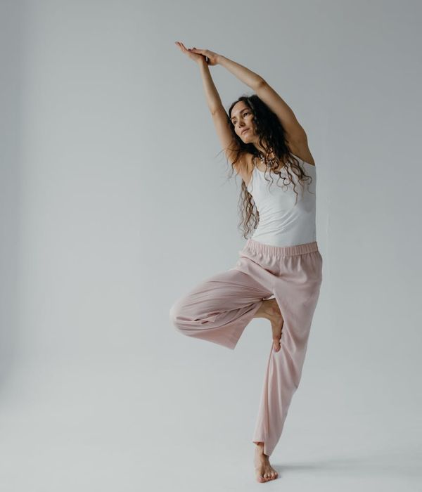Woman in a peaceful yoga pose in a bright, minimalist studio.